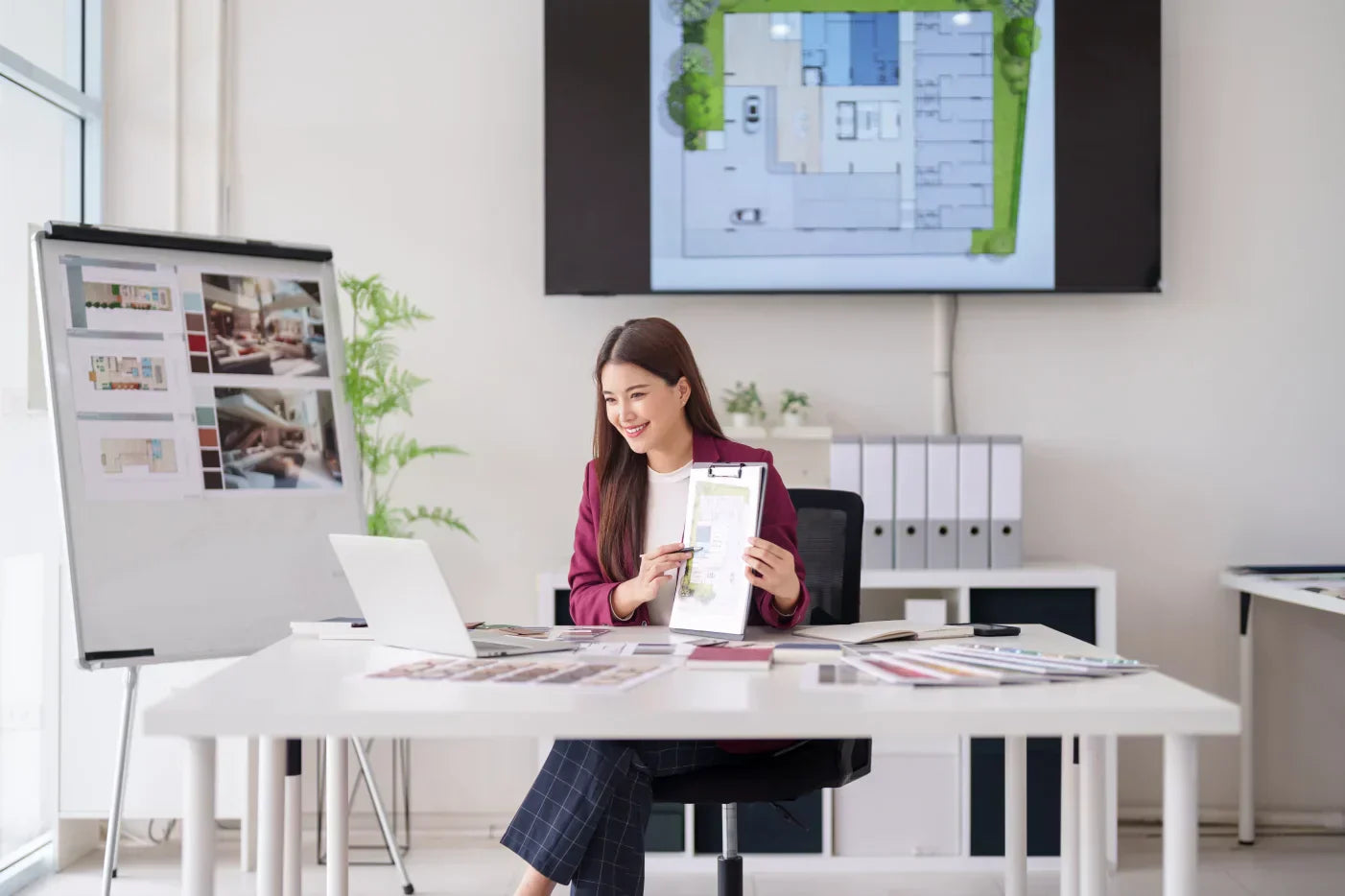 A lady sitting on a desk chair presenting something to an online conference