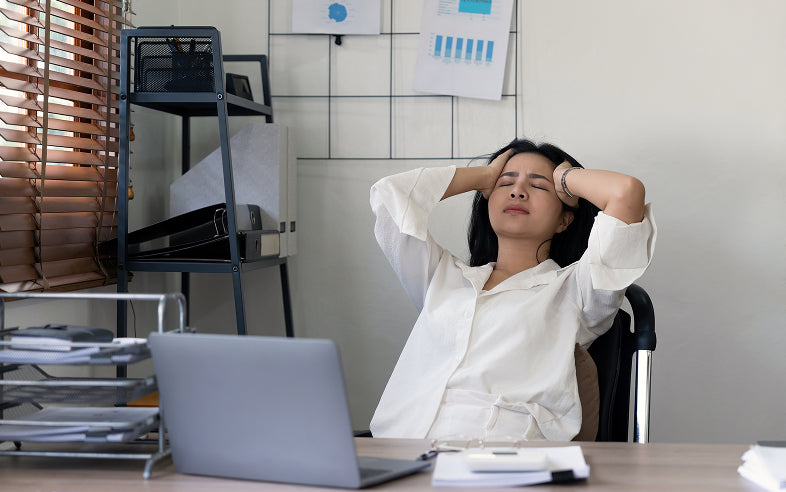 Stressed office worker holding her head from task switching fatigue.