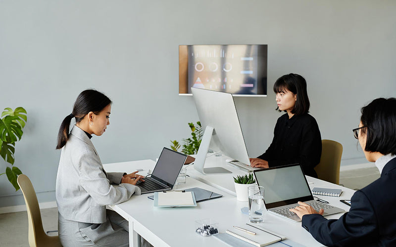 Employees working at an ergonomic shared office workstation layout.