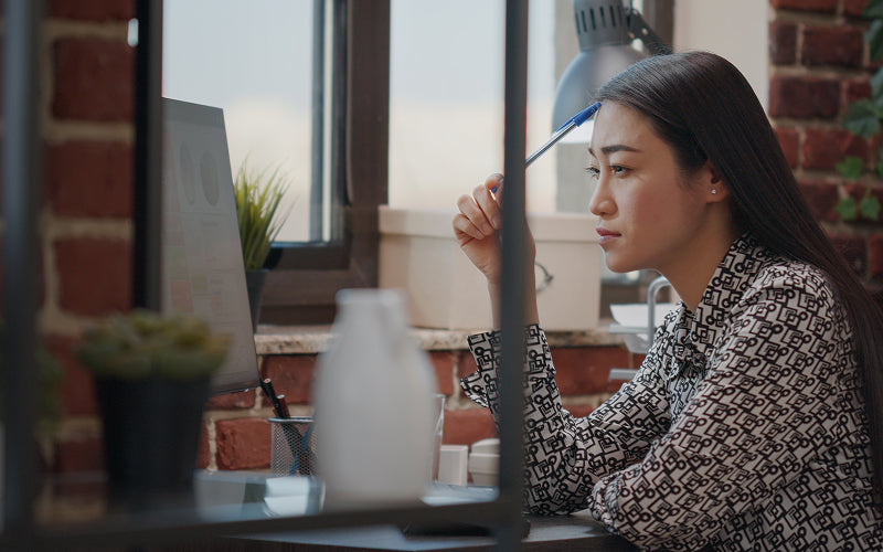 Focused woman experiencing eye strain while looking at computer screen.